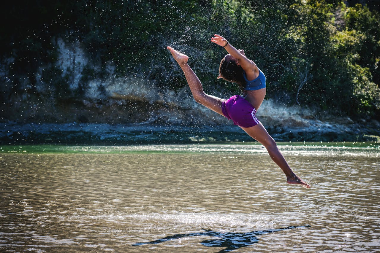 services-img-04 Young woman leaps in front of a river, showcasing flexibility and energy.